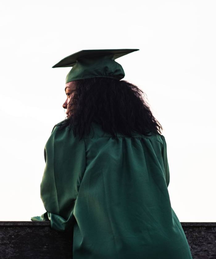 girl in green cap and gown looking in the distant